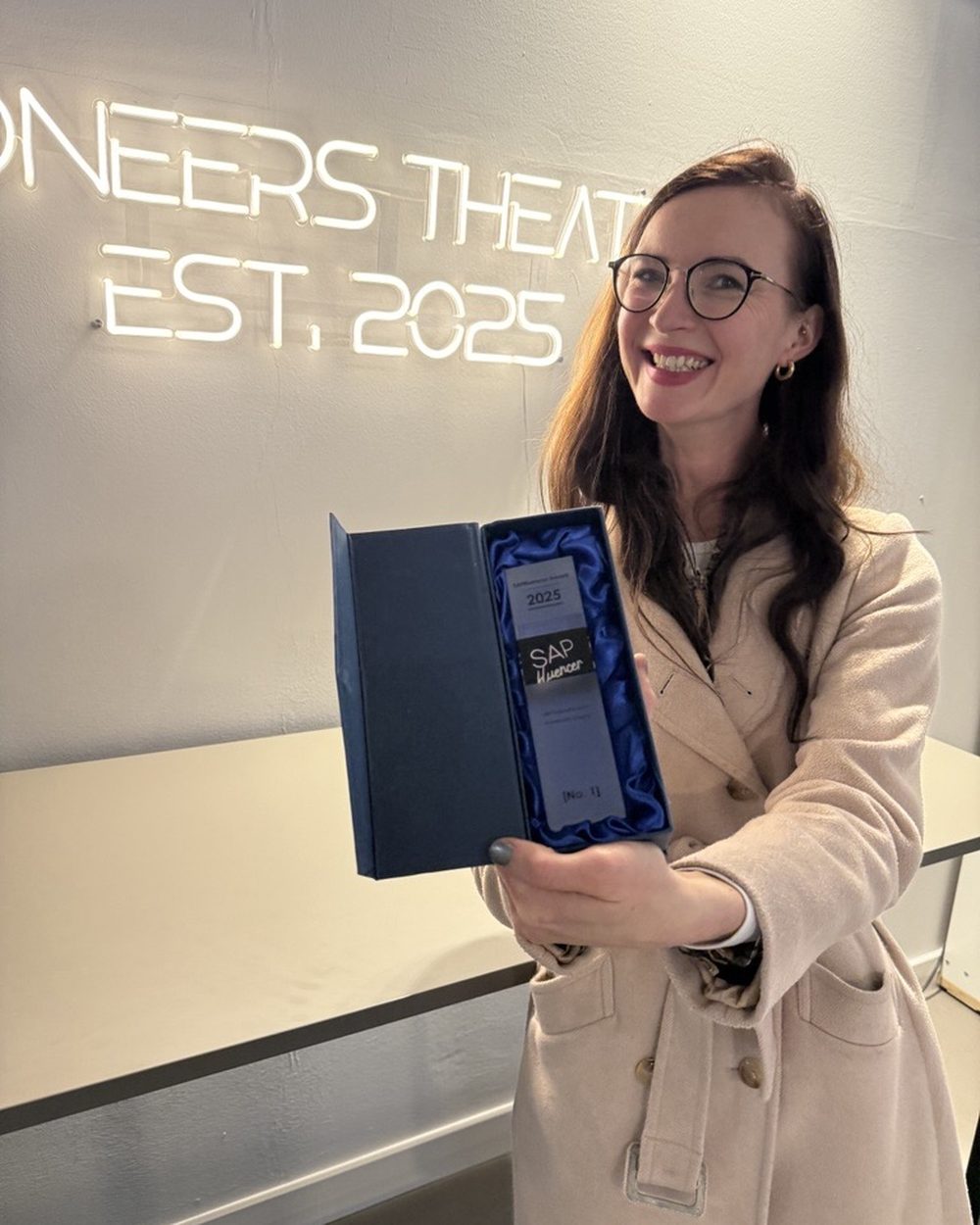 Sarah Niesel mit der Trophäe vor der Neonschrift Pioneers Theatre